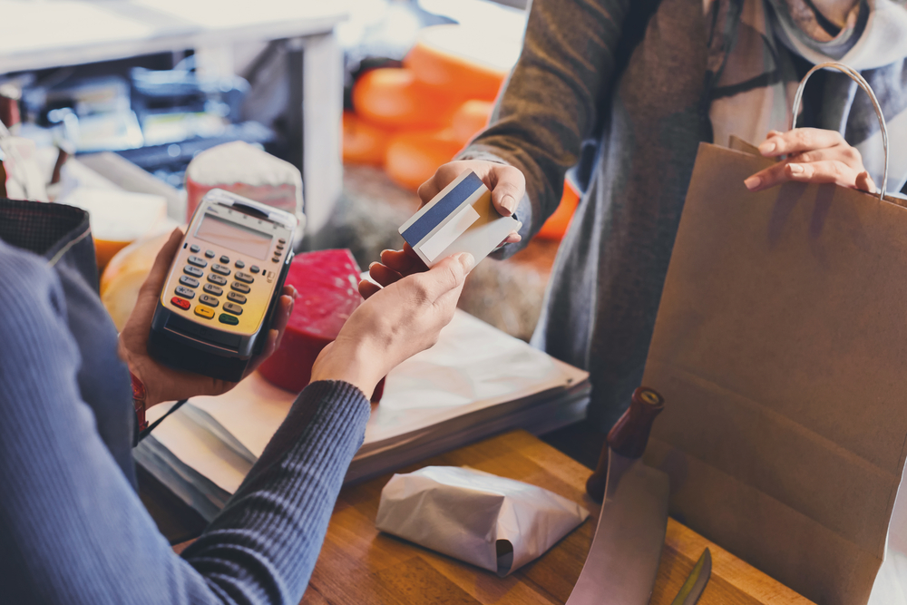 Uma pessoa entrega o cartão de crédito para a caixa para realizar um pagamento.