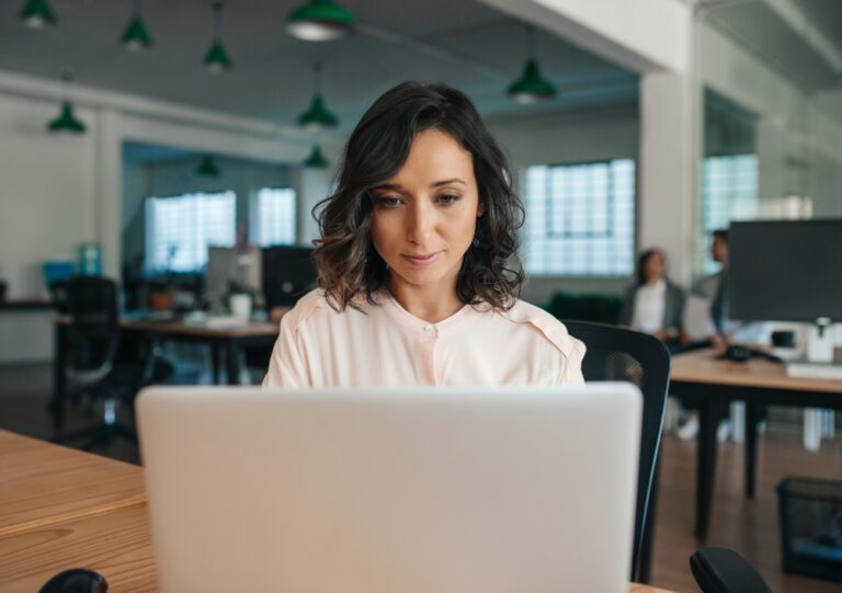 Uma mulher trabalhando em um notebook em um ambiente de escritório.