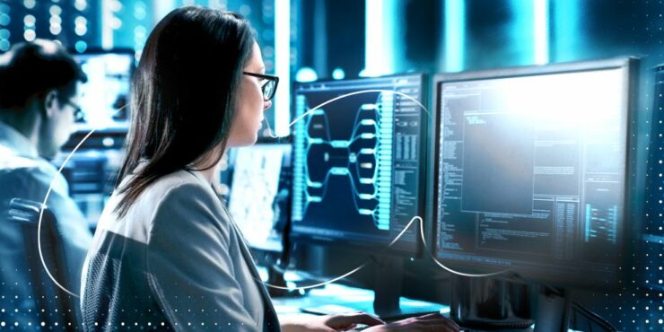 Uma mulher olha para a tela de um computador, na qual aparecem sistemas de segurança.